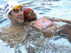 Michael Phelps ensinando uma aluna a flutuar na água. Michael Phelps ensinando uma aluna a flutuar na água.